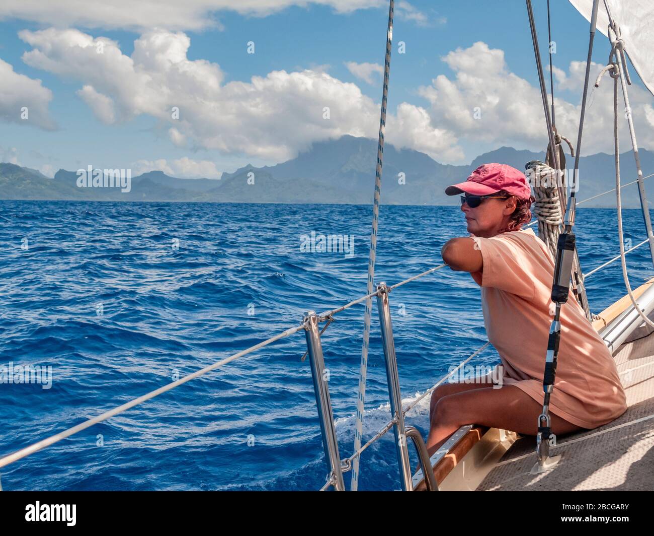 Junge Frau auf einer Segelyacht, nähert sich der Insel Raiatea vom Meer, Französisch-Polynesien, Gesellschaftsinseln, südpazifik Stockfoto