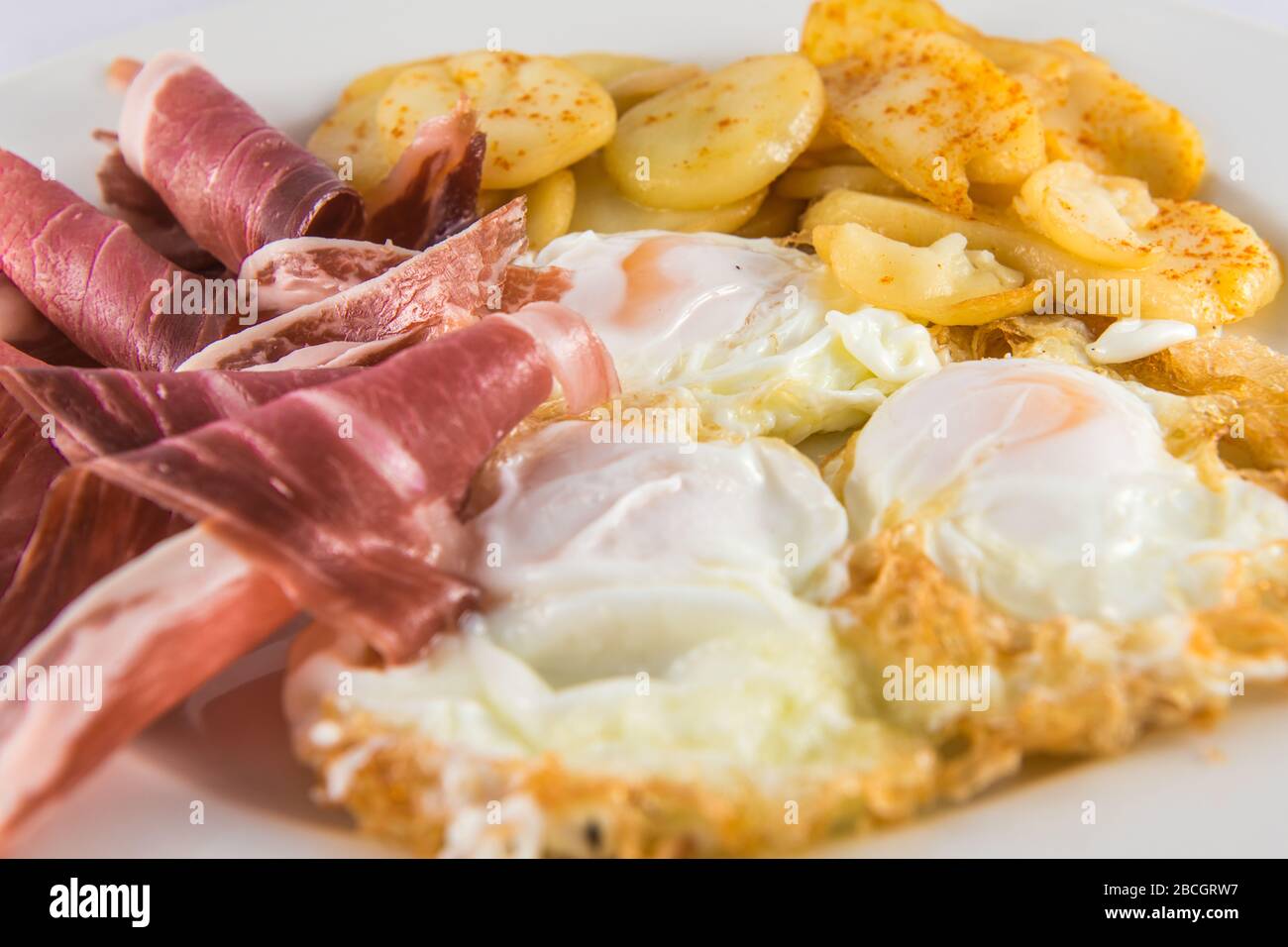Teller mit zerbrochenen Eiern mit Schinken und Kartoffeln. Stockfoto