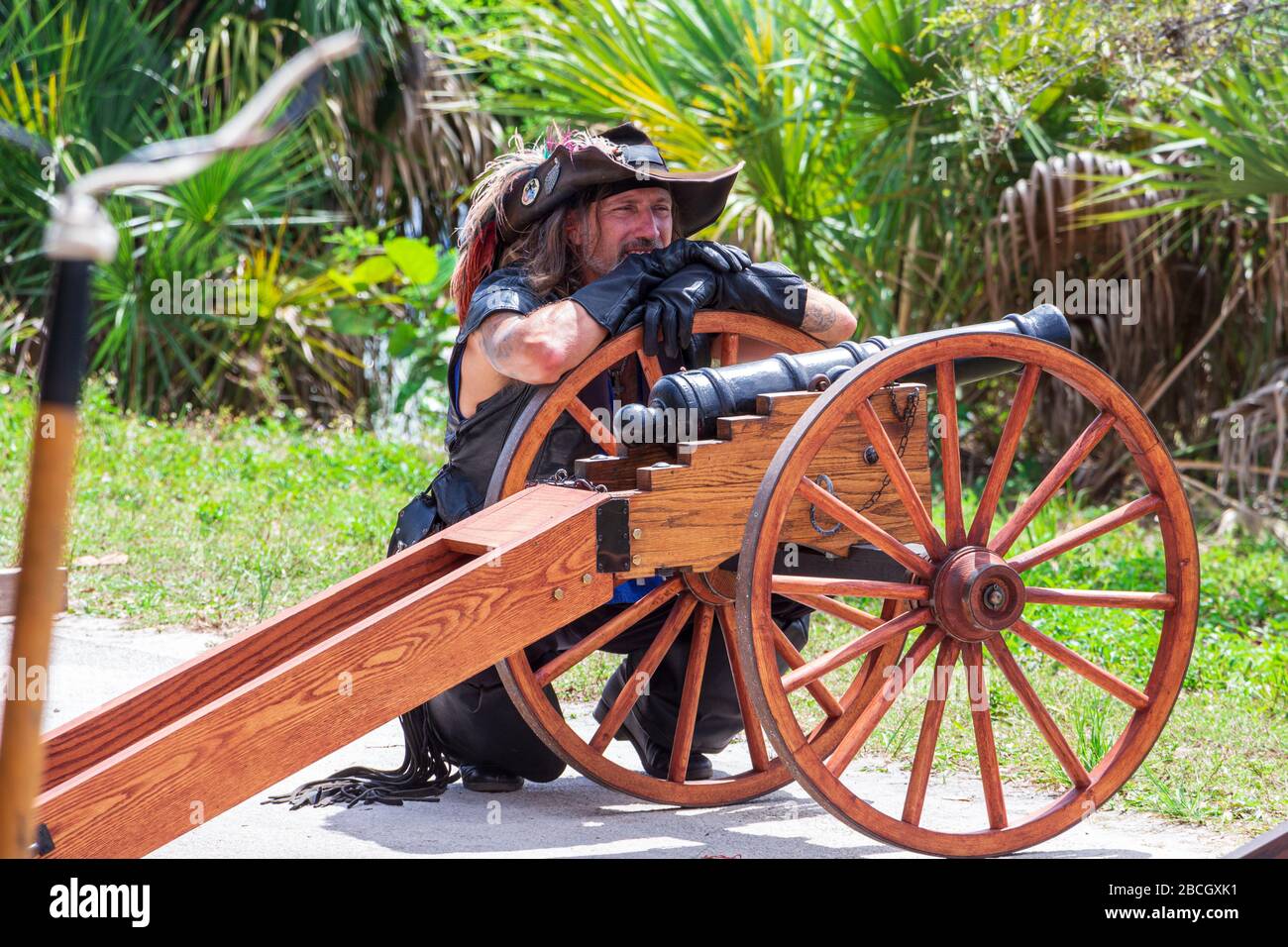 Ein Piratendarsteller lehnt sich beim Florida Renaissance Festival - Quiet Waters Park, Deerfield Beach, Florida, USA, an eine Kanone an Stockfoto