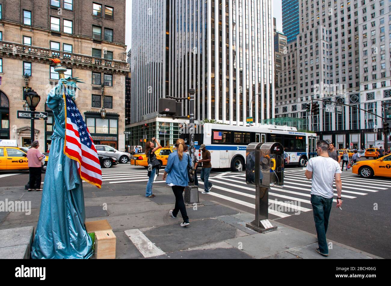 Eine in Freiheitsstatue gekleidete Menschenstatue mit Touristen, die darauf warten, am Ausgang des Central Park plaza mit Blick auf die Grand Army Plaz fotografiert zu werden Stockfoto