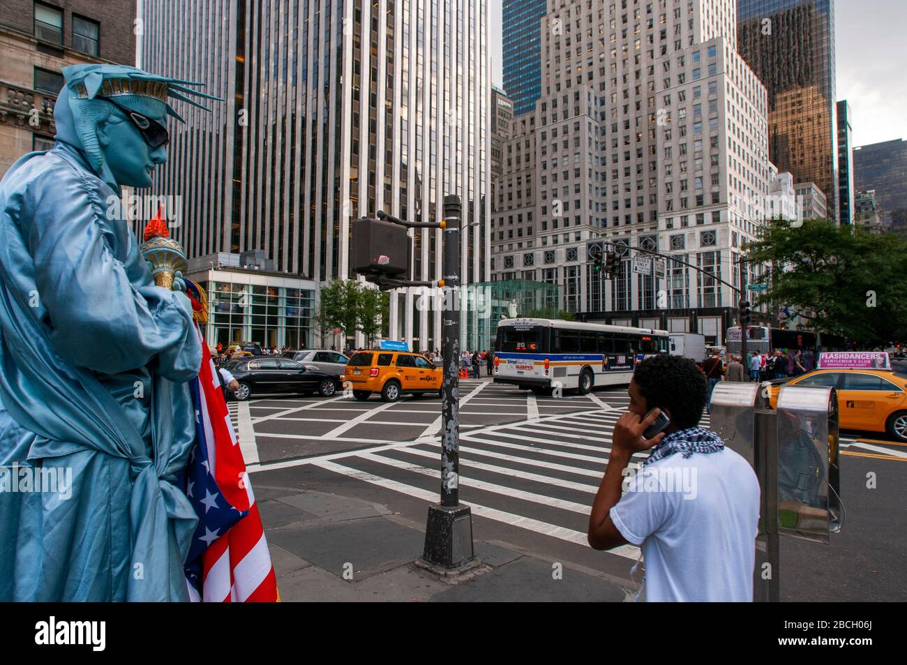 Eine in Freiheitsstatue gekleidete Menschenstatue mit Touristen, die darauf warten, am Ausgang des Central Park plaza mit Blick auf die Grand Army Plaz fotografiert zu werden Stockfoto