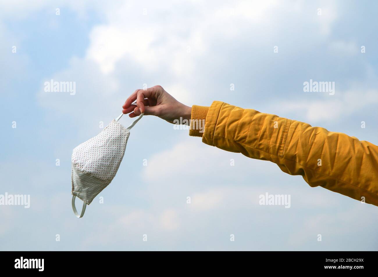 Frau hält die textile hausgemachte Gesichtsmaske, die zum Schutz vor Viren verwendet wird, während sie in der Natur spaziert. Stockfoto