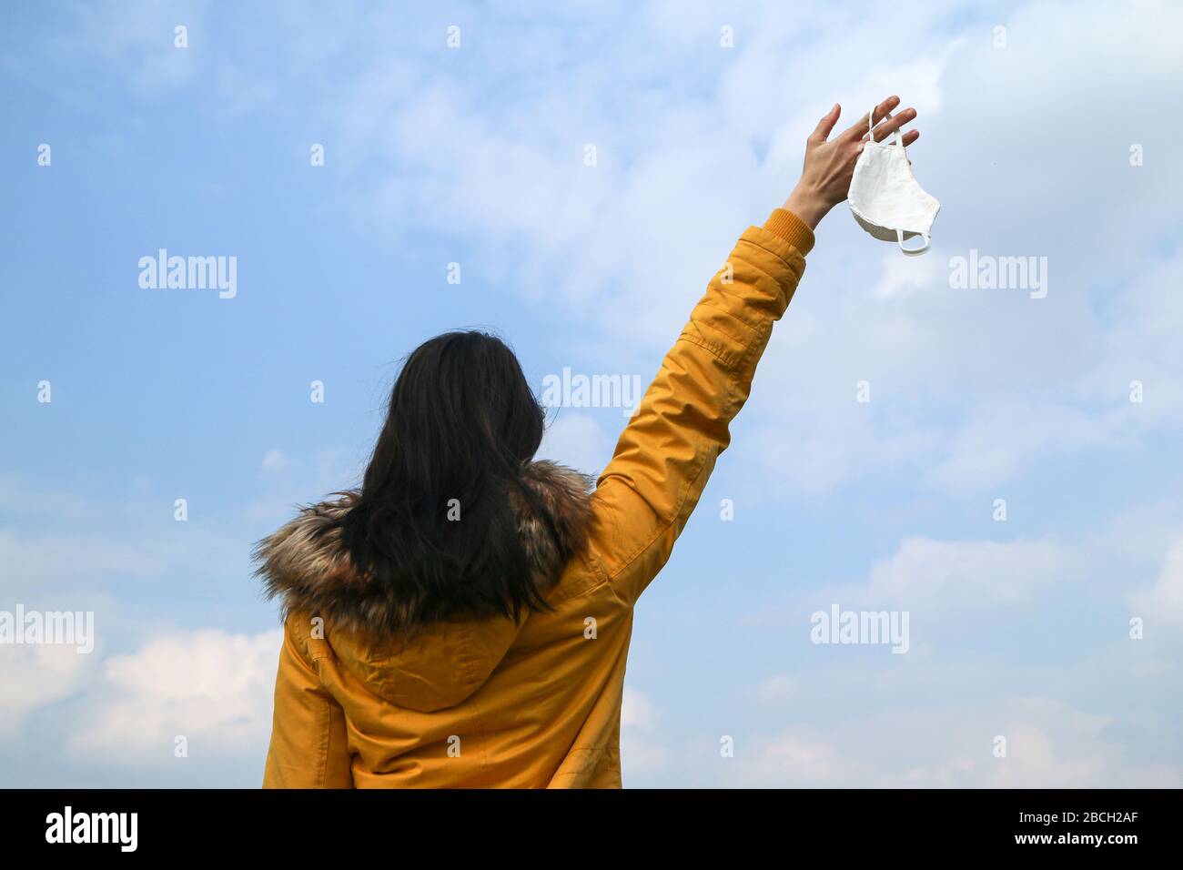 Frau hält die textile hausgemachte Gesichtsmaske, die zum Schutz vor Viren verwendet wird, während sie in der Natur spaziert. Stockfoto