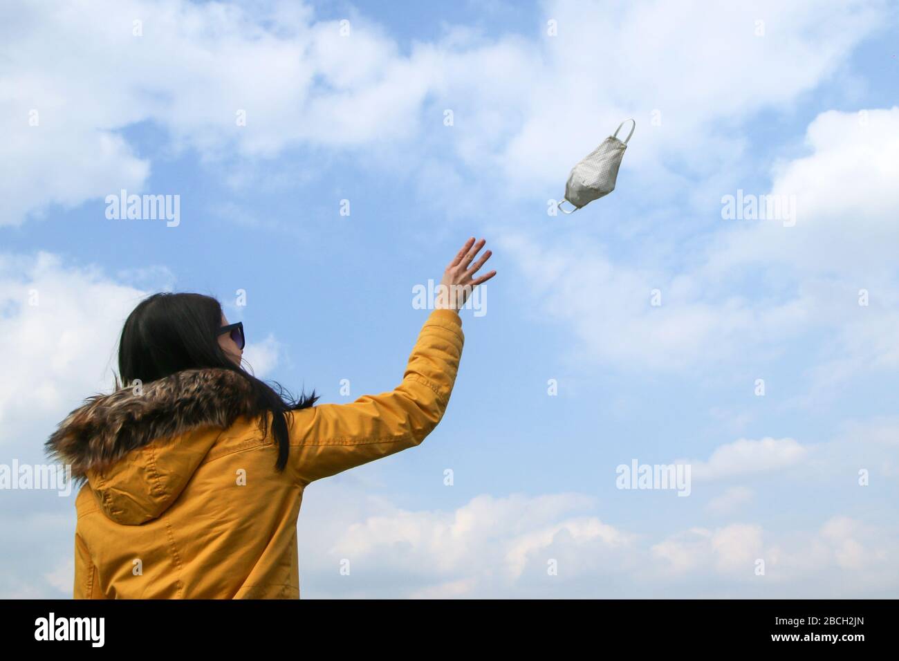 Frau wirft die textile Hausmaske weg, die zum Schutz vor Viren beim Wandern in der Natur verwendet wird. Stockfoto