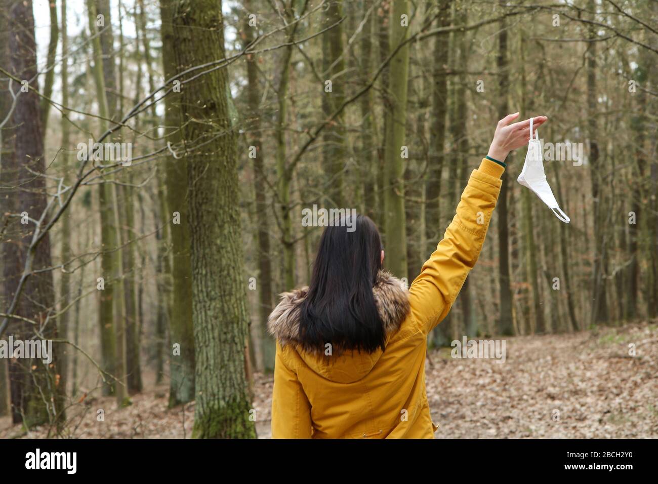 Frau hält die textile hausgemachte Gesichtsmaske, die zum Schutz vor Viren verwendet wird, während sie in der Natur spaziert. Stockfoto