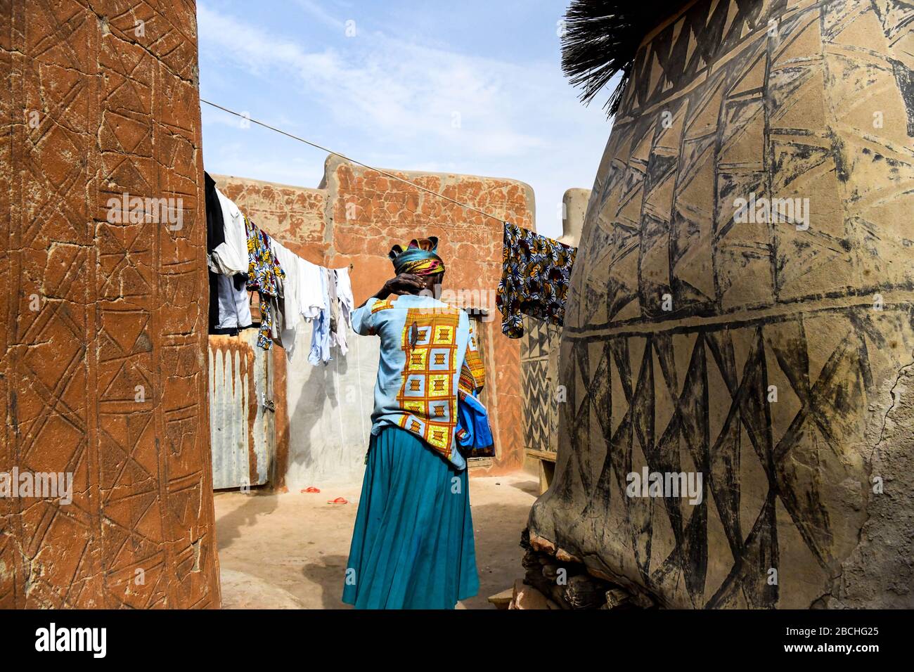 Afrika, Burkina Faso, Region Pô, Tiebele. Stadtansicht des königlichen Hofdorfes in Tiebele. Eine Frau geht, um Wäsche aufzuhängen Stockfoto