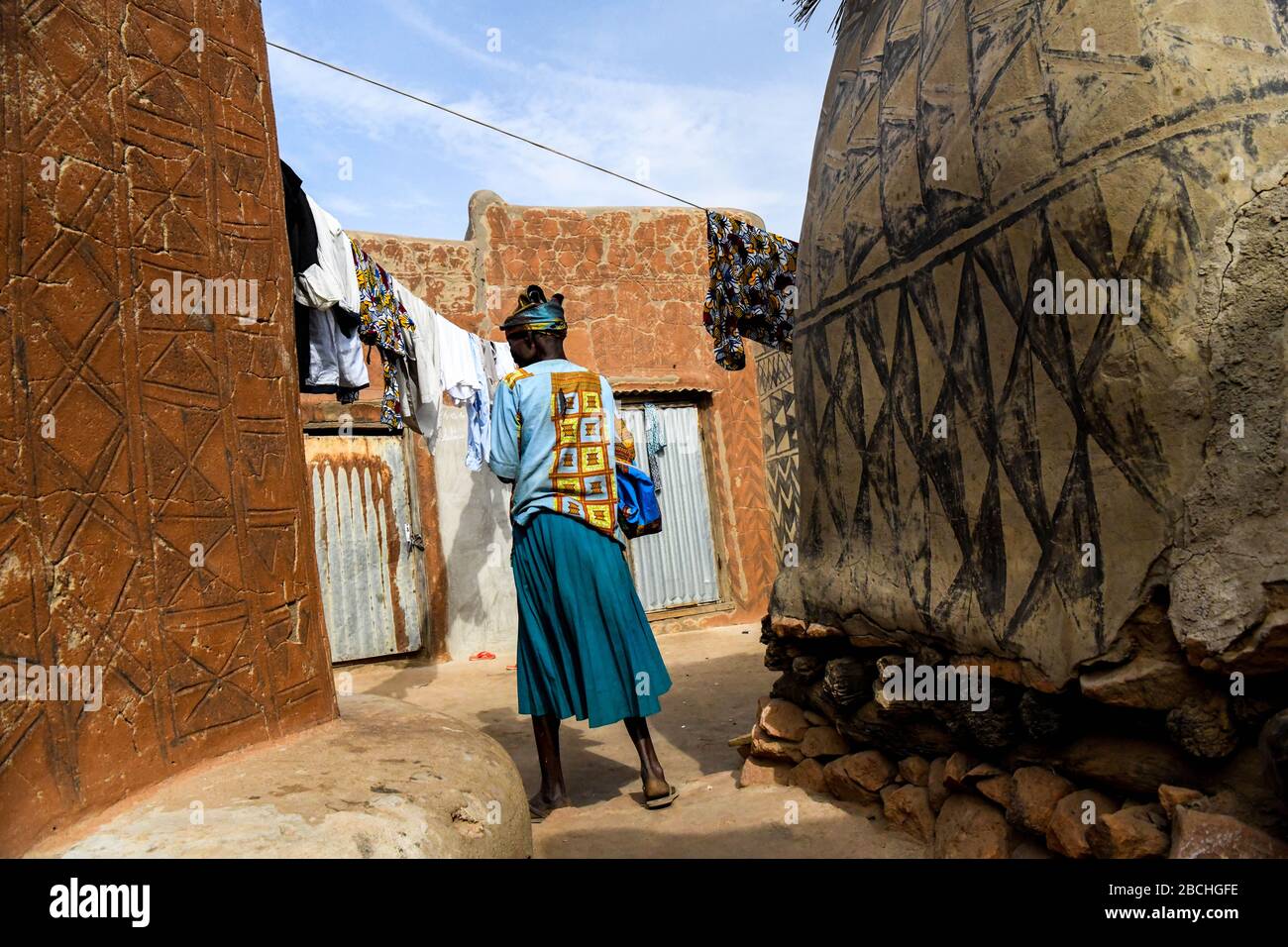 Afrika, Burkina Faso, Region Pô, Tiebele. Stadtansicht des königlichen Hofdorfes in Tiebele. Eine Frau geht, um Wäsche aufzuhängen Stockfoto