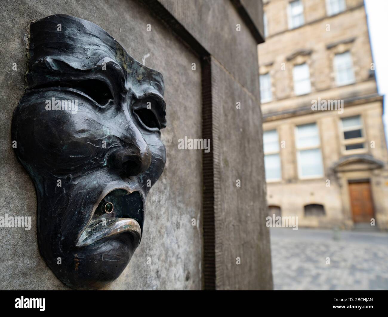 Theatralische Maske Bronzerelation mit traurigem Gesicht auf der High Street Wellhead auf der Royal Mile in Edinburgh, Schottland, Großbritannien, um auf Traurigkeit der Annullierung des Edinburgh Fringe Festivals 2020 hinzuweisen. Stockfoto