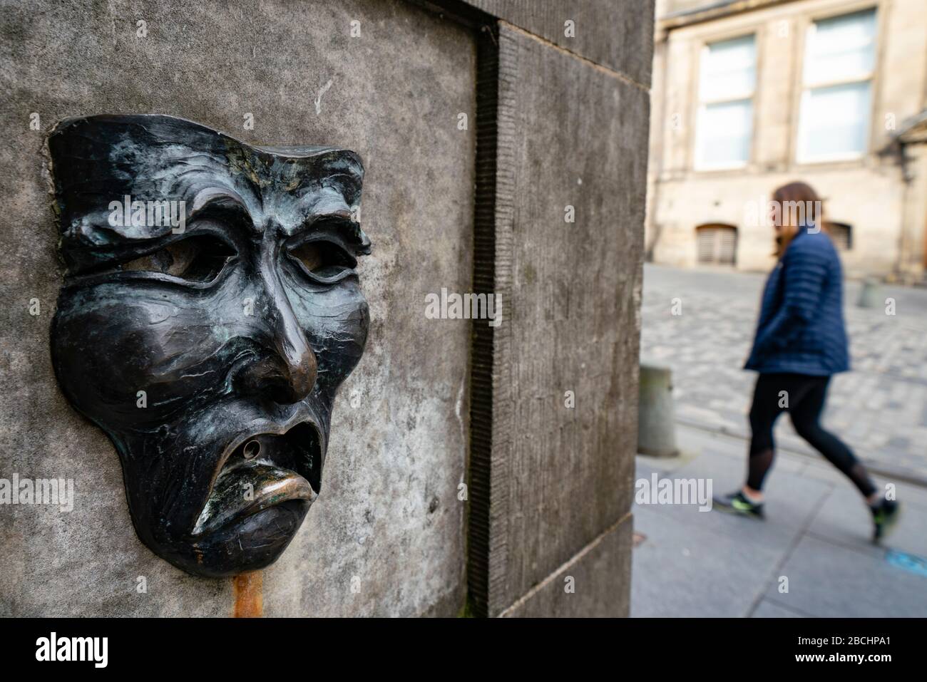 Theatralische Maske Bronzerelation mit traurigem Gesicht auf der High Street Wellhead auf der Royal Mile in Edinburgh, Schottland, Großbritannien, um auf Traurigkeit der Annullierung des Edinburgh Fringe Festivals 2020 hinzuweisen. Stockfoto