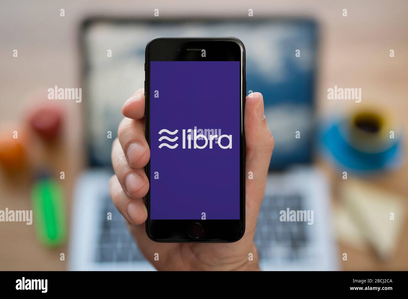 Ein Mann betrachtet sein iPhone, auf dem das Facebook-Libra-Logo (nur redaktionelle Verwendung) angezeigt wird. Stockfoto