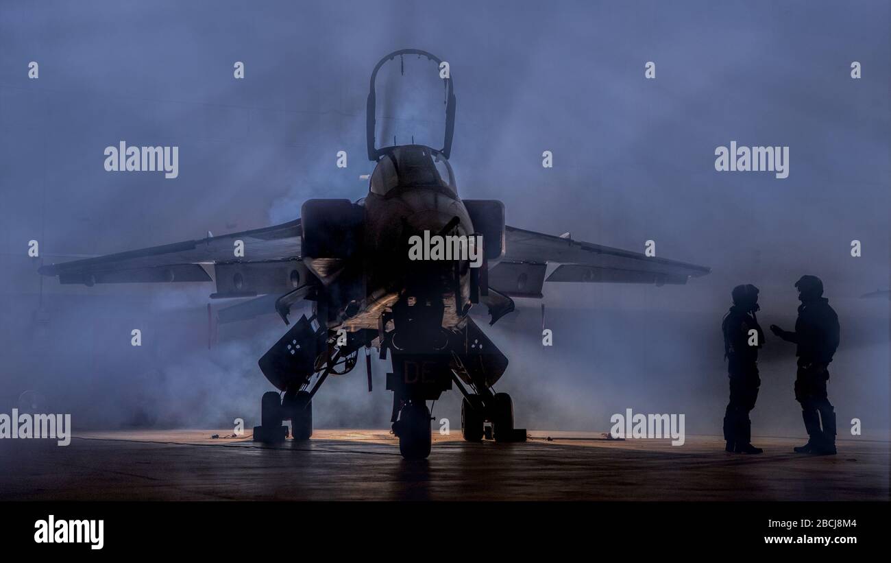 Piloten diskutieren Kampfmission mit einem Angriffskämpfer. Pilotensilhouetten, die über ihre fliegende Mission reden, umgeben von Rauch. Stockfoto