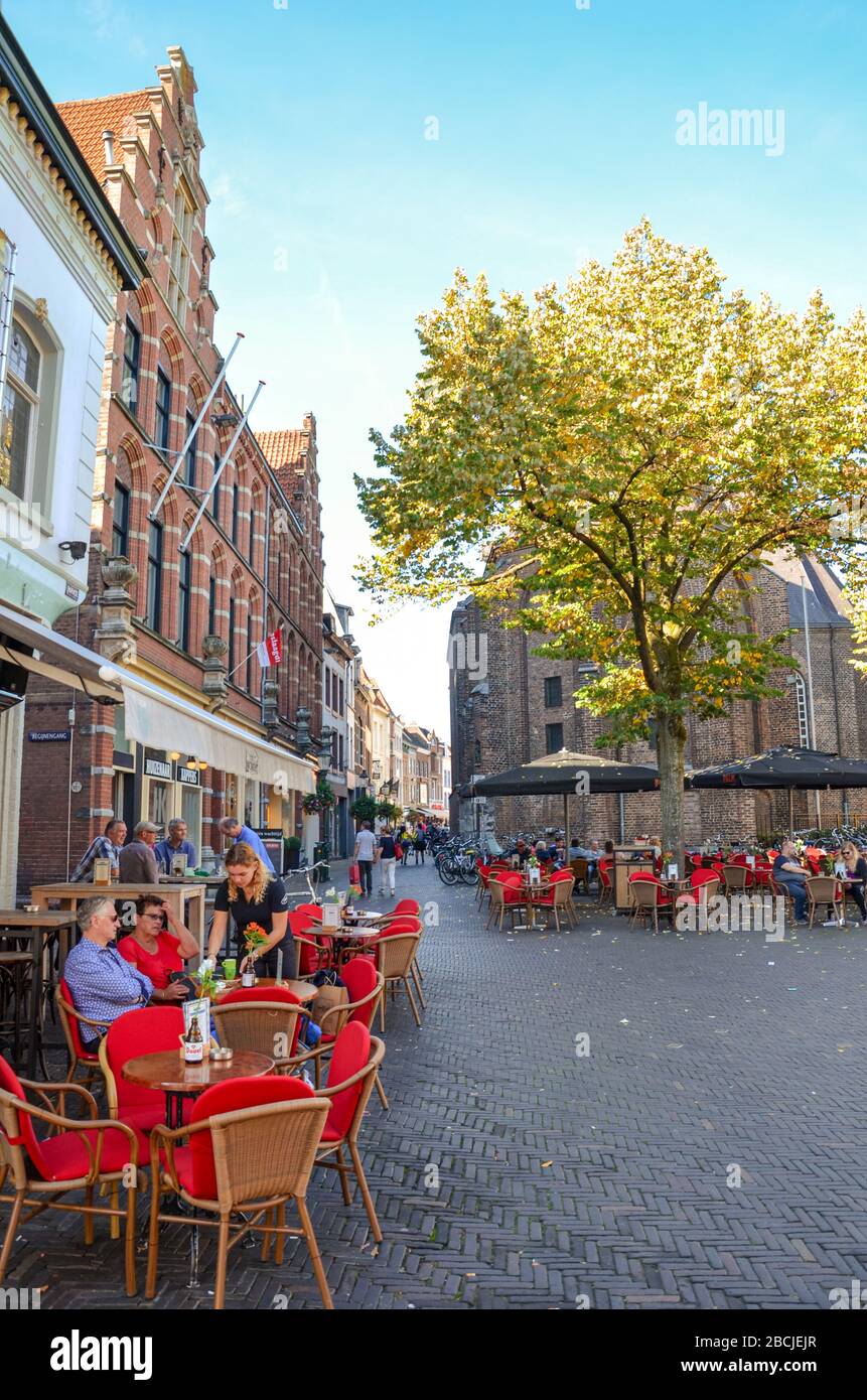 Venlo, Limburg-Niederlande - 13. Oktober 2018: Straße mit Cafés, Restaurants und Bars im historischen Zentrum der niederländischen Stadt. Leute, die in den Gärten sitzen. Vertikales Foto. Stockfoto