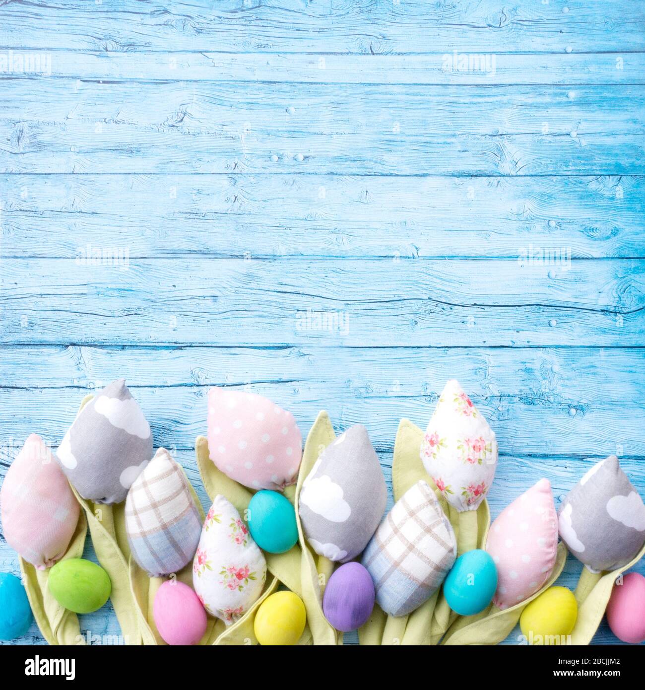 Textile Tulpen und ostereier auf blauen rustikalen Brettern für osterkarte oder instagram-Grußpost. Ostern Blumenrahmen für Urlaub Verkauf Ankündigung oder Stockfoto