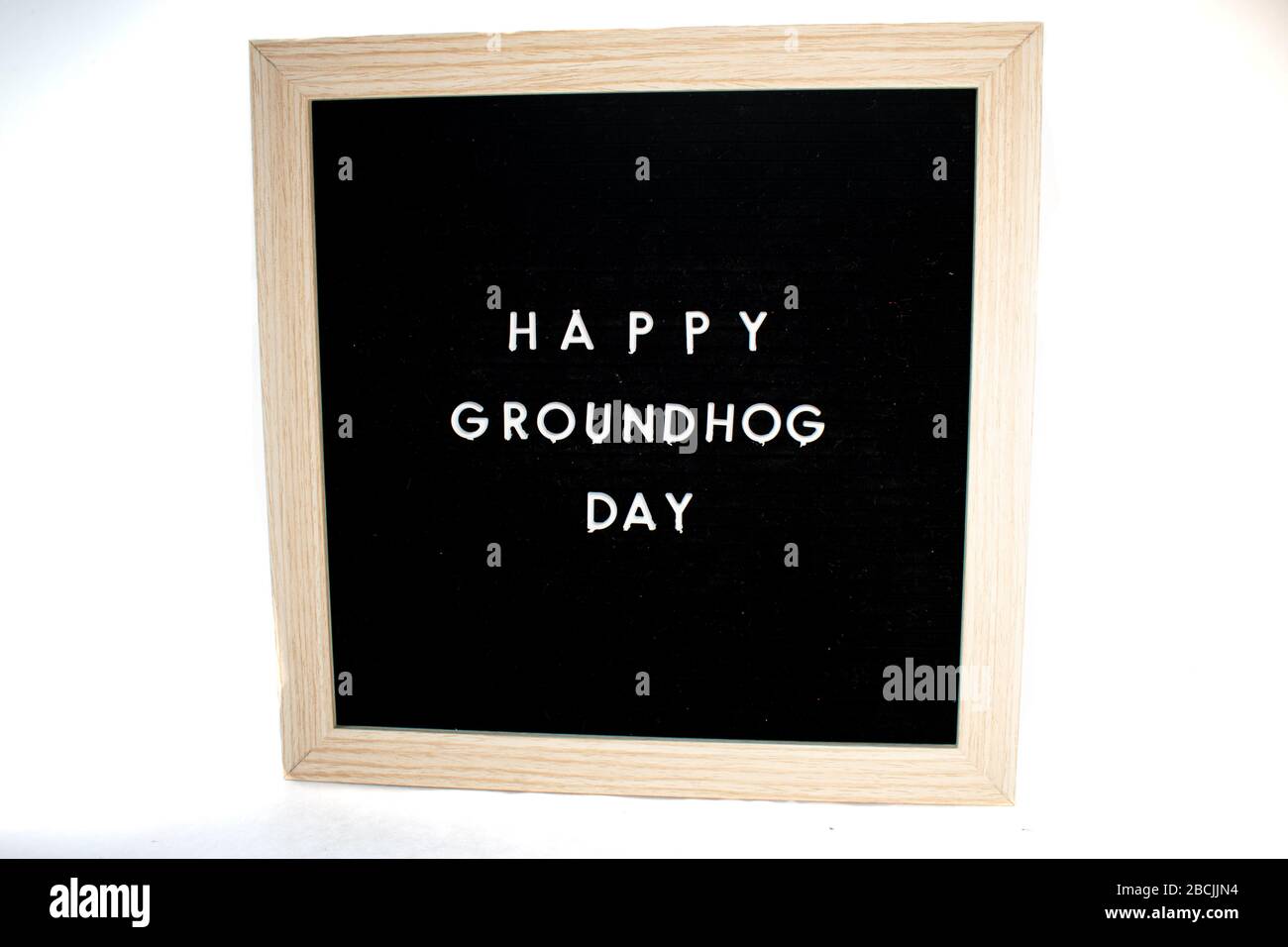 Ein schwarzes Schild mit weißen Buchstaben, die Happy Groundhog Day auf einem weißen Hintergrund sagt Stockfoto