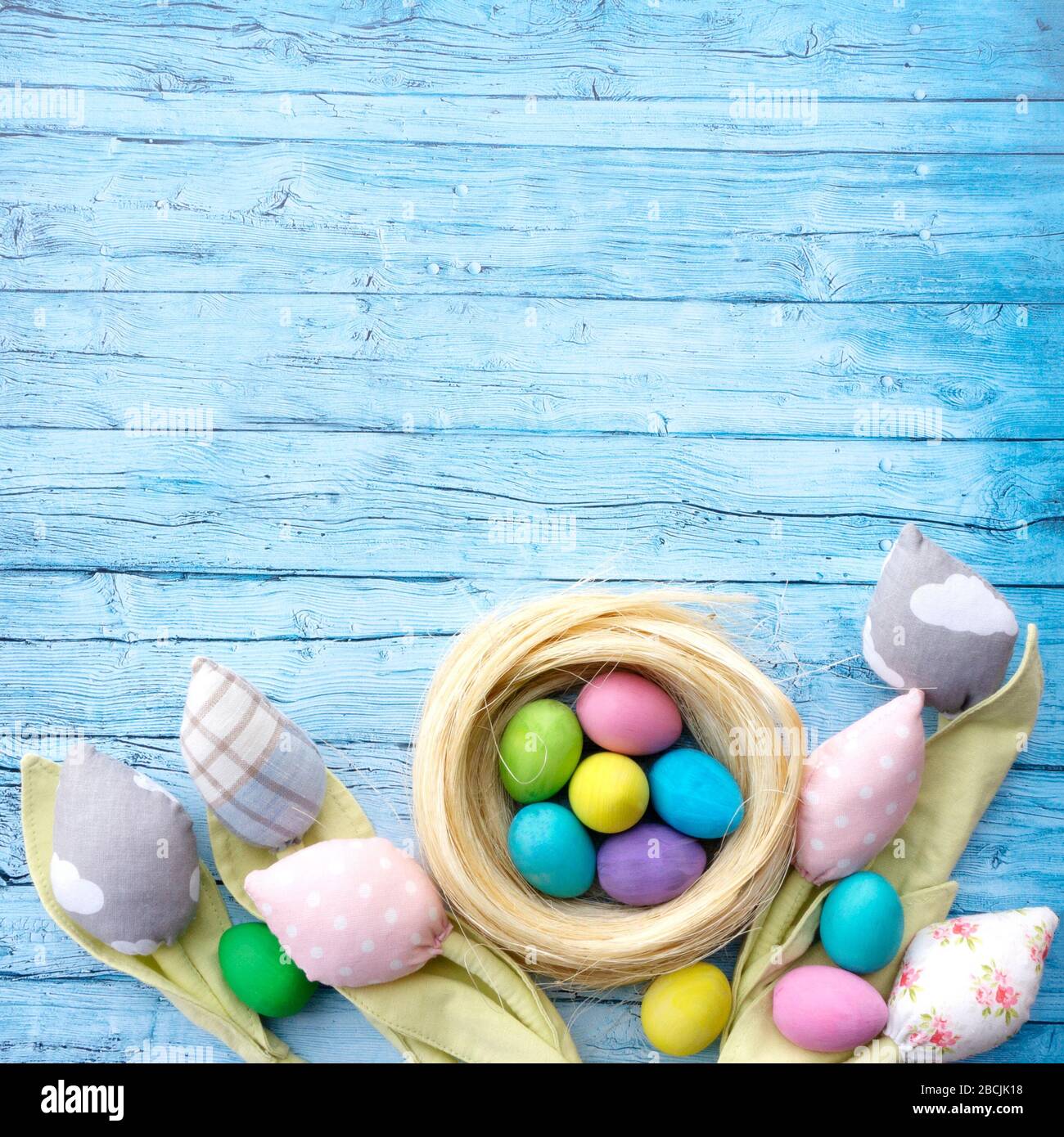 Rustikale ostern Hintergrund für Werbung oder Banner, Instagram Post. Patchwork Tulpen aus Textil und bunten Ostereiern auf einem Hintergrund von blu Stockfoto