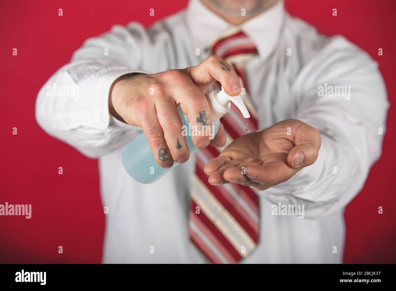 Man Hände mit Desinfektionsmittel für das Händewaschen, gegen die neue Coronavirus- oder Corona-Viruserkrankung auf rotem Grund. Stockfoto