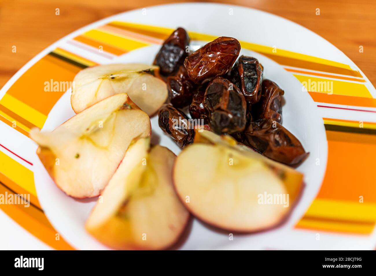 Nahaufnahme von rohen veganen gesunden Snacks oder Zutaten mit getrockneten medjool-datteln und in Scheiben geschnittenen Äpfeln auf Plattenmakro Stockfoto