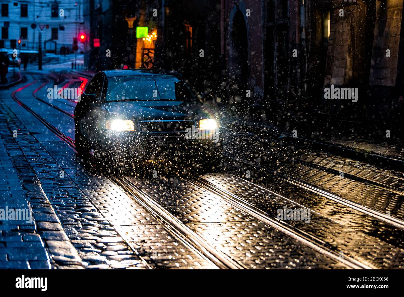 Lwiw, Ukraine Altstadt in Lvov nachts mit Schneewetterstraße und Auto in Gasse mit Reflexion von Scheinwerfern und Schneeflocken im Winter Stockfoto