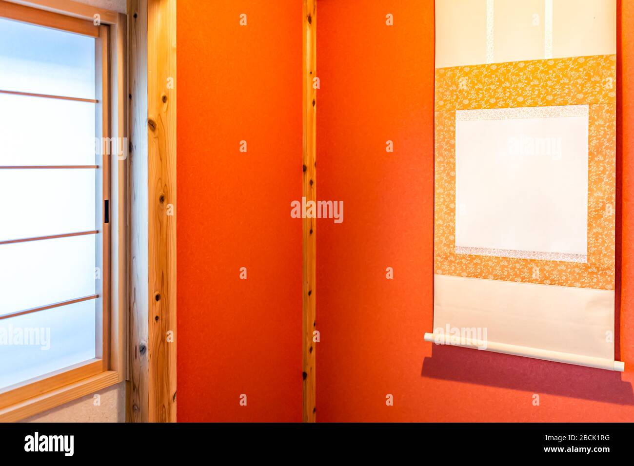Traditionelles rotes japanisches Haus oder Ryokan mit Fenster und Nische mit tokonoma hängender Schriftrolle und orangefarbener Millionen gelber Farbe Stockfoto