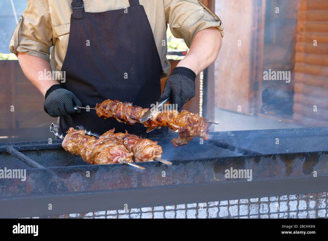 Der Mensch brat Fleisch auf einem offenen Feuer.Street Food und Outdoor-Kochkonzept Stockfoto