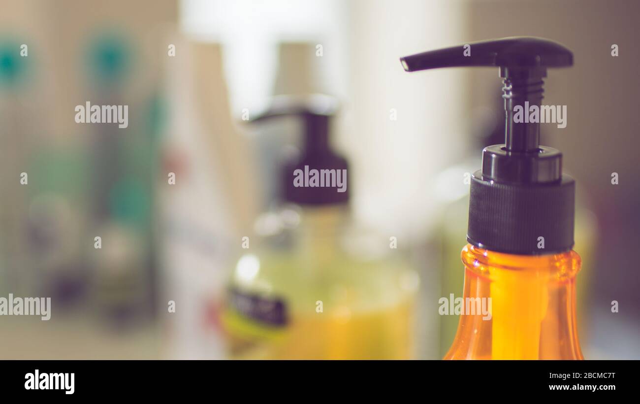 Orangefarbene Cremeflasche mit schwarzem Spender auf einem Regal im Badezimmer Stockfoto