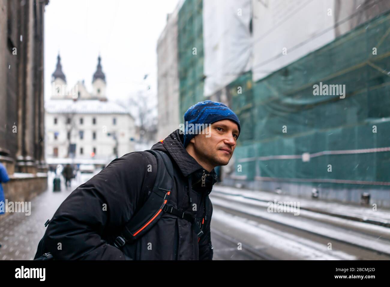 Lwiw, Ukraine Straße in der Altstadt in der Nähe des Marktplatzes im Winter in Lvov mit Weihnachten kalten Schnee und Mann in Mantel Rucksack Reisen warten an der Bushaltestelle Loo Stockfoto