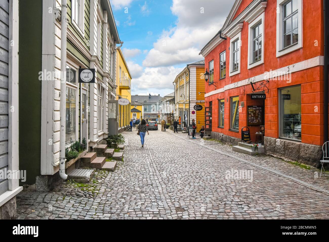 Touristen genießen Sehenswürdigkeiten und Einkaufsmöglichkeiten auf einer der Kopfsteinpflasterstraßen in der farbenfrohen, mittelalterlichen Stadt Porvoo, Finnland. Stockfoto
