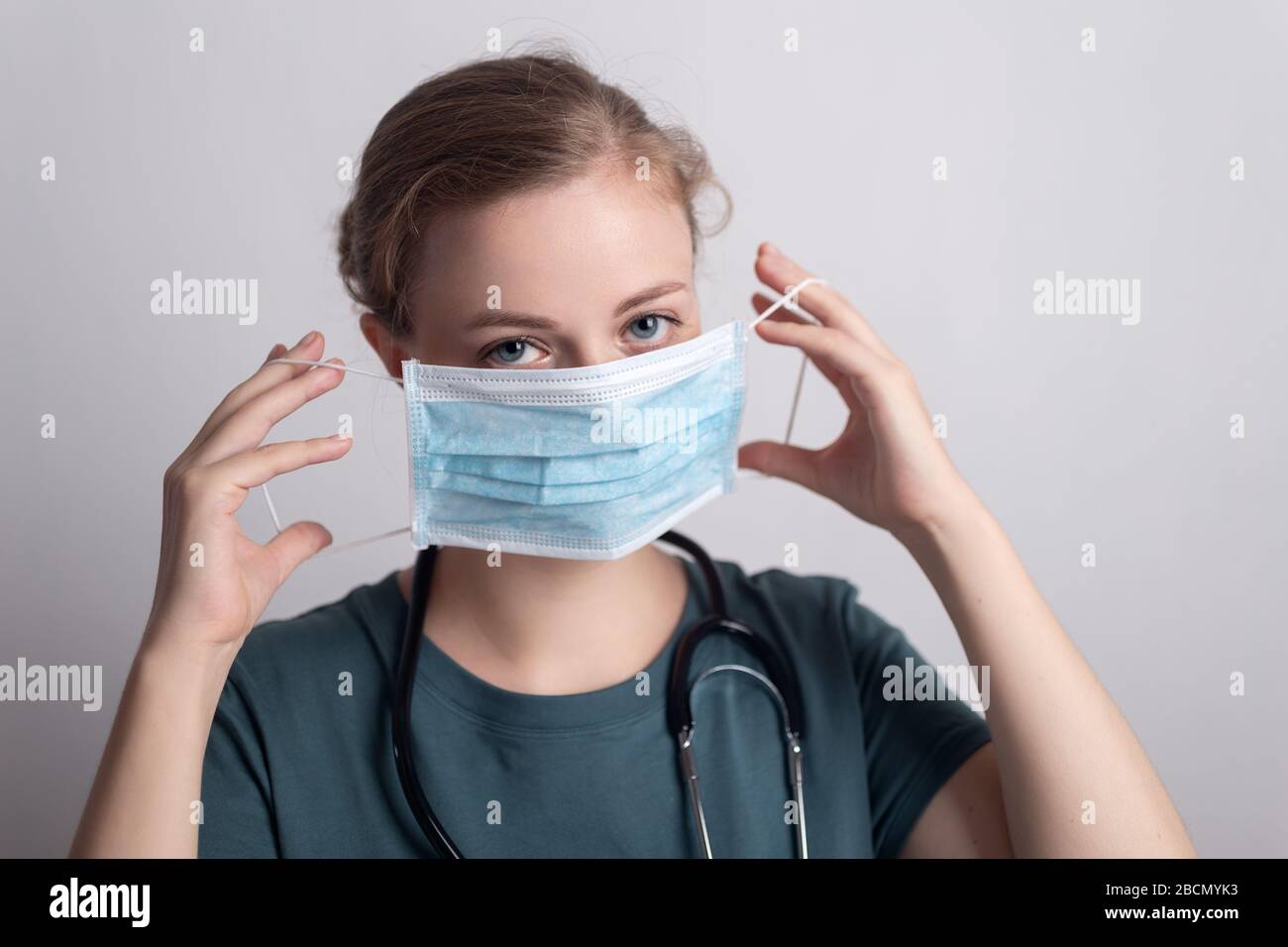 Weibliche kaukasische Arztschwester Frau mit chirurgischer Maske Stockfoto