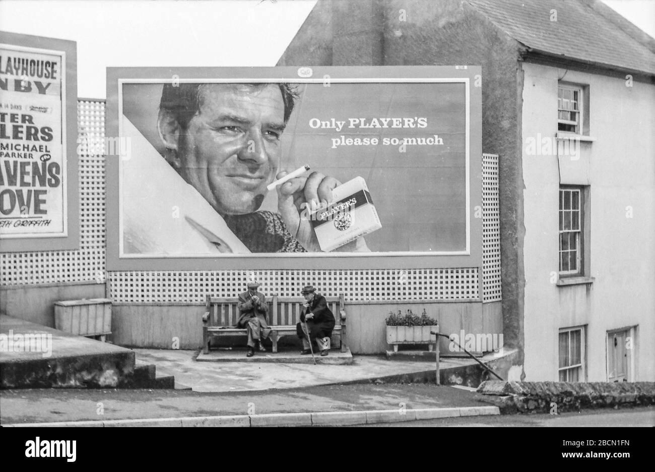 Reklametafeln aus den 60er Jahren über zwei alte Männer auf Bank sitzen und plaudern. Schwarz und Weiß Stockfoto