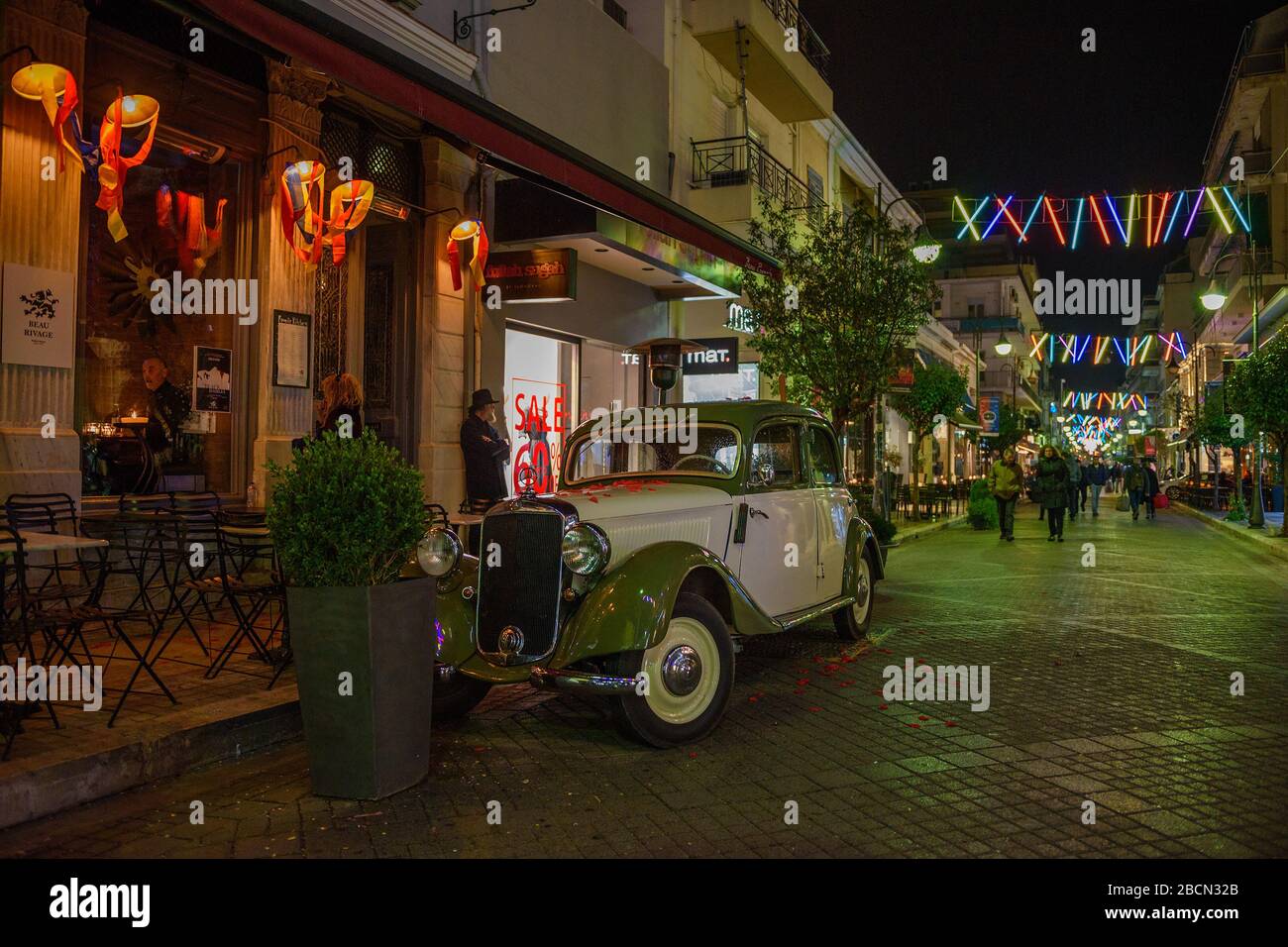 Der alte, antike Mercedes Benz Wagen parkte in der berühmten Rigaer Fereou Fußgängerzone der Stadt Patras, die für den berühmten Karneval in Patras dekoriert ist. Stockfoto