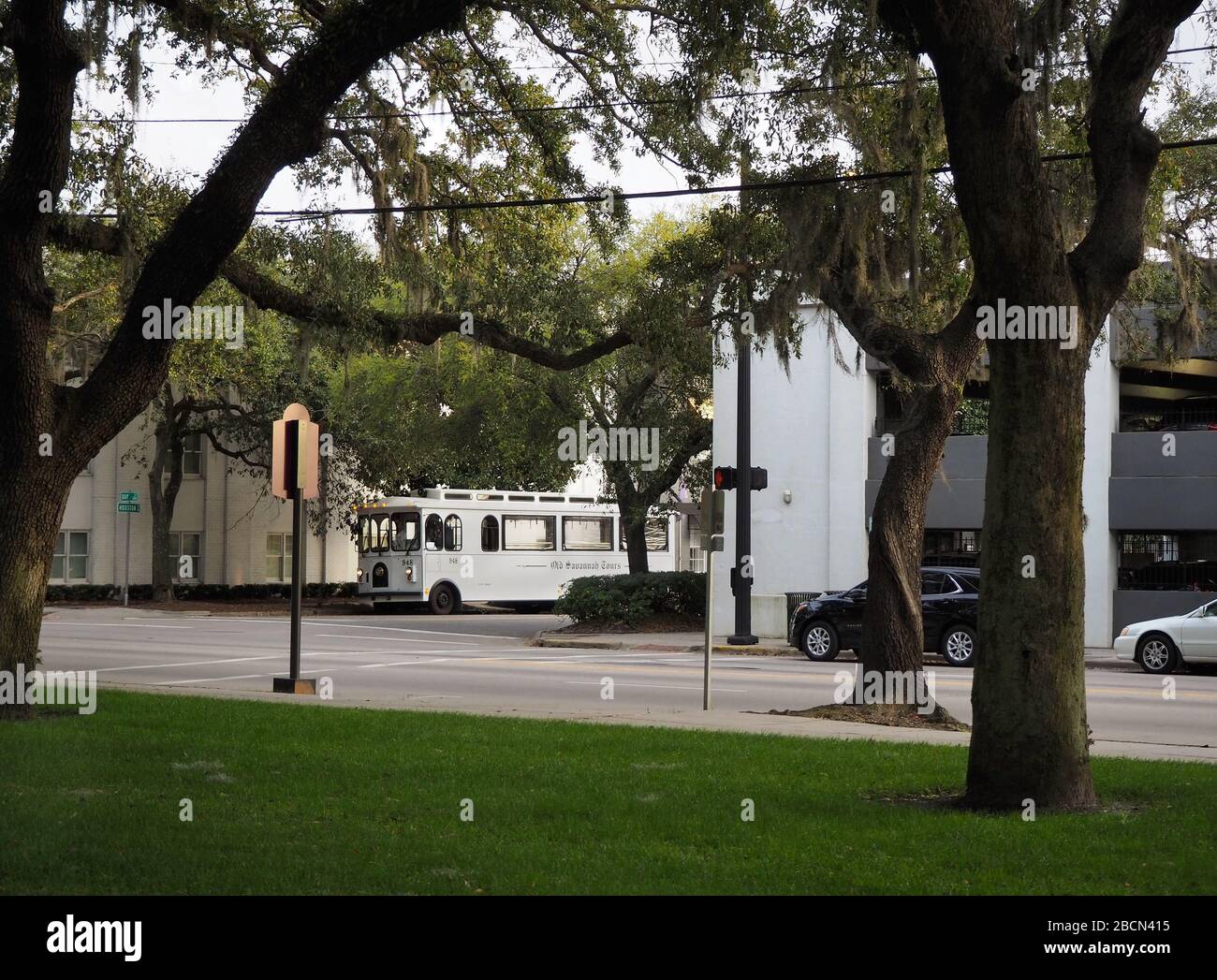 SAVANNAH, GEORGIA - 23. FEBRUAR 2020: Ein alter weißer Trolly-Bus, der eine Stadtrundfahrt gibt, kann durch Eiche gesehen werden, die mit dem spanischen Moss A tropft Stockfoto