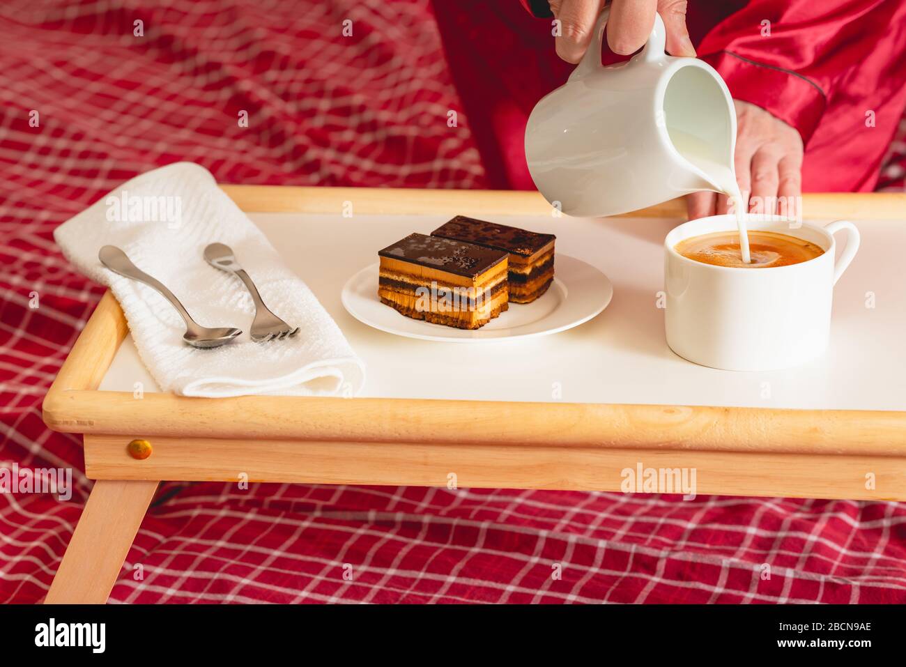 Tasse Kaffee mit Milch und Schokoladenkuchen. Süßes köstliches Frühstück auf einem Tisch mit Betttablett Stockfoto