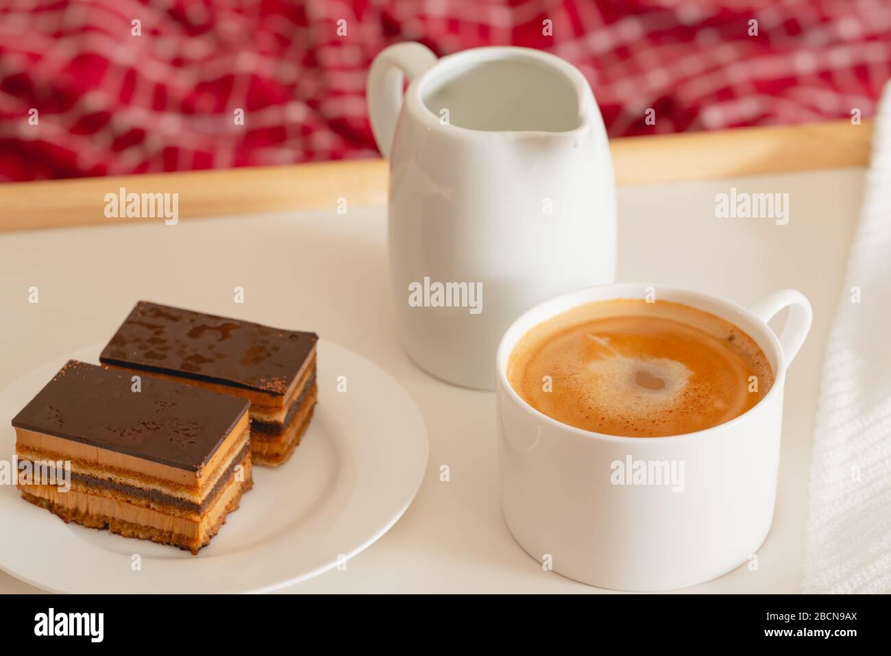 Tasse Kaffee mit Milch und Schokoladenkuchen. Süßes köstliches Frühstück auf einem Tisch mit Betttablett Stockfoto