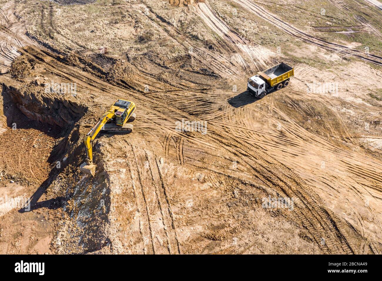 Luftbild des Baggers, der Sand in den Kippwagen auf der Baustelle lädt Stockfoto