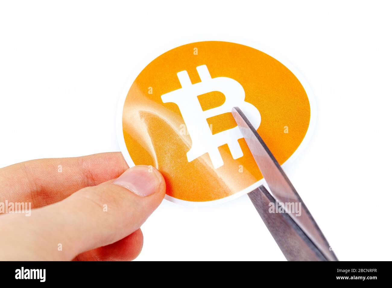 Bitcoin-Symbol wird in der Hälfte mit Schere in der Hand des Menschen, Rückgang der digitalen Währung Bitcoin-Preise fallen Kryptokurrency Tod, verlieren Wert Stockfoto