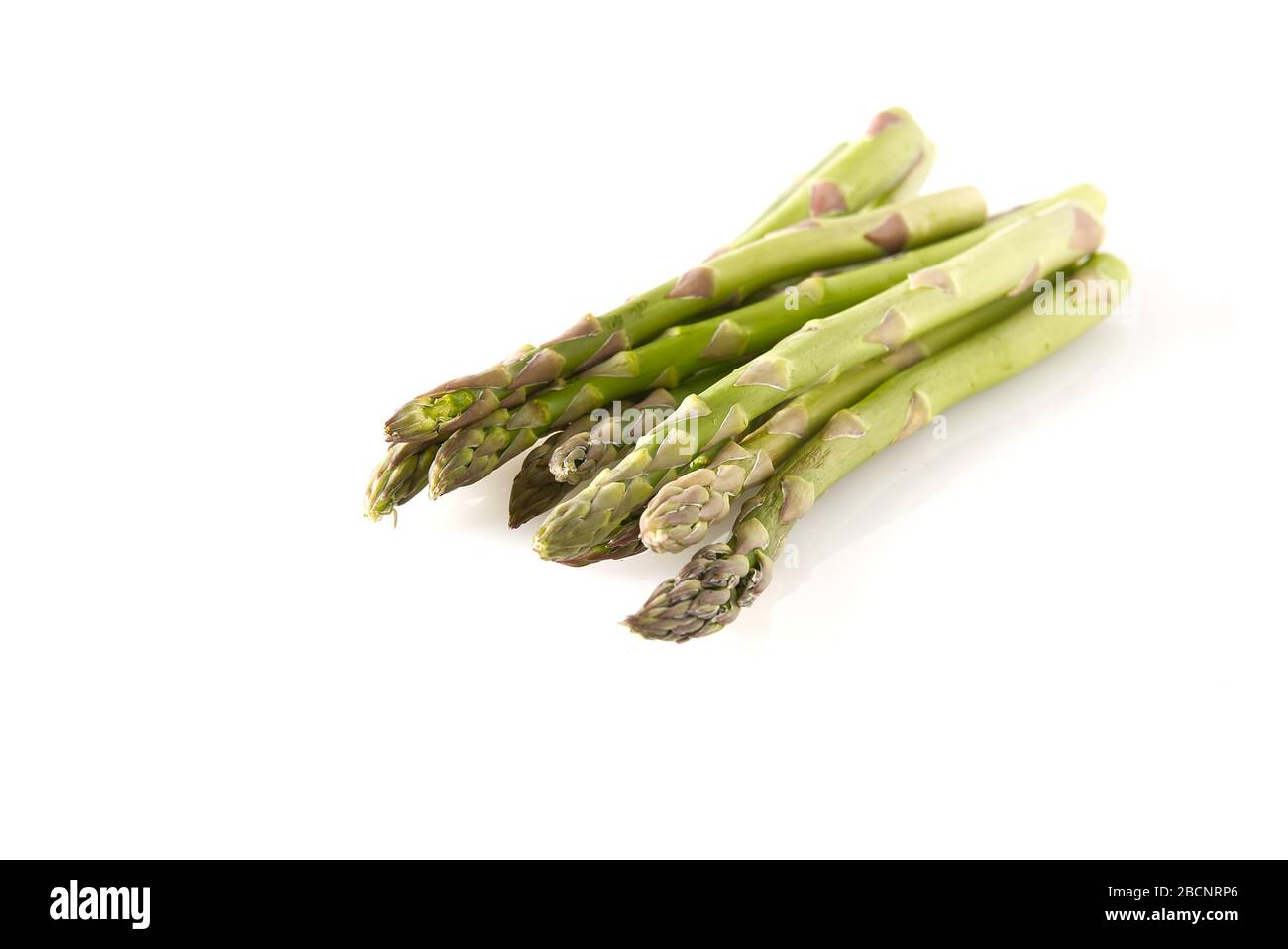 Bio-Spargel auf weißem Hintergrund isoliert. Grüner Spargel im Garten Boden, isoliert Stockfoto