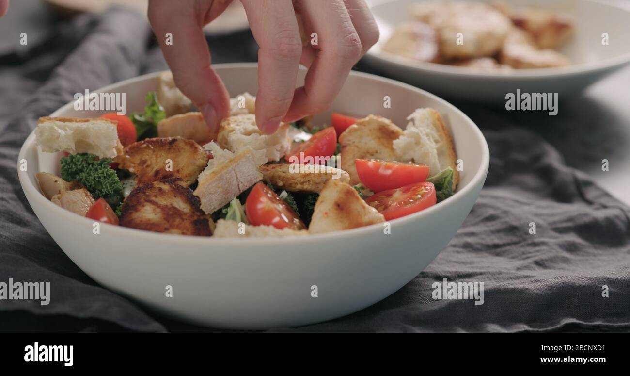 Mann Hände caesar Salat mit Grünkohl und truthahn in einer weißen Schüssel, fügen Croutons Stockfoto