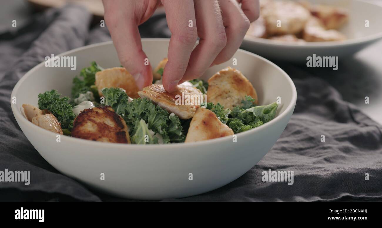 Mann Hände caesar Salat mit Grünkohl und truthahn in einer weißen Schüssel, fügen sie pute Stockfoto