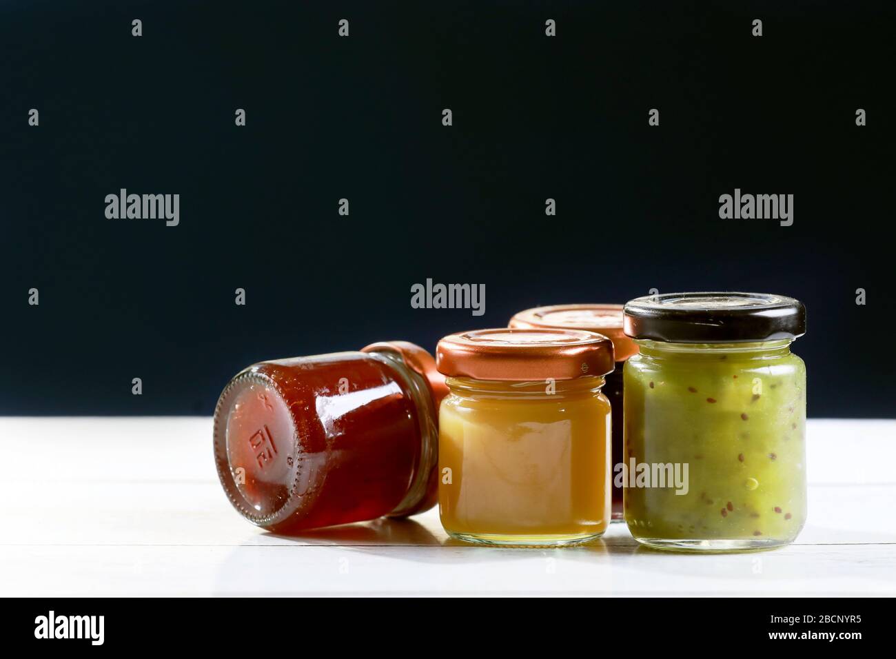 Glas Glas hausgemachte Marmelade auf Holztisch und schwarzem Hintergrund Stockfoto