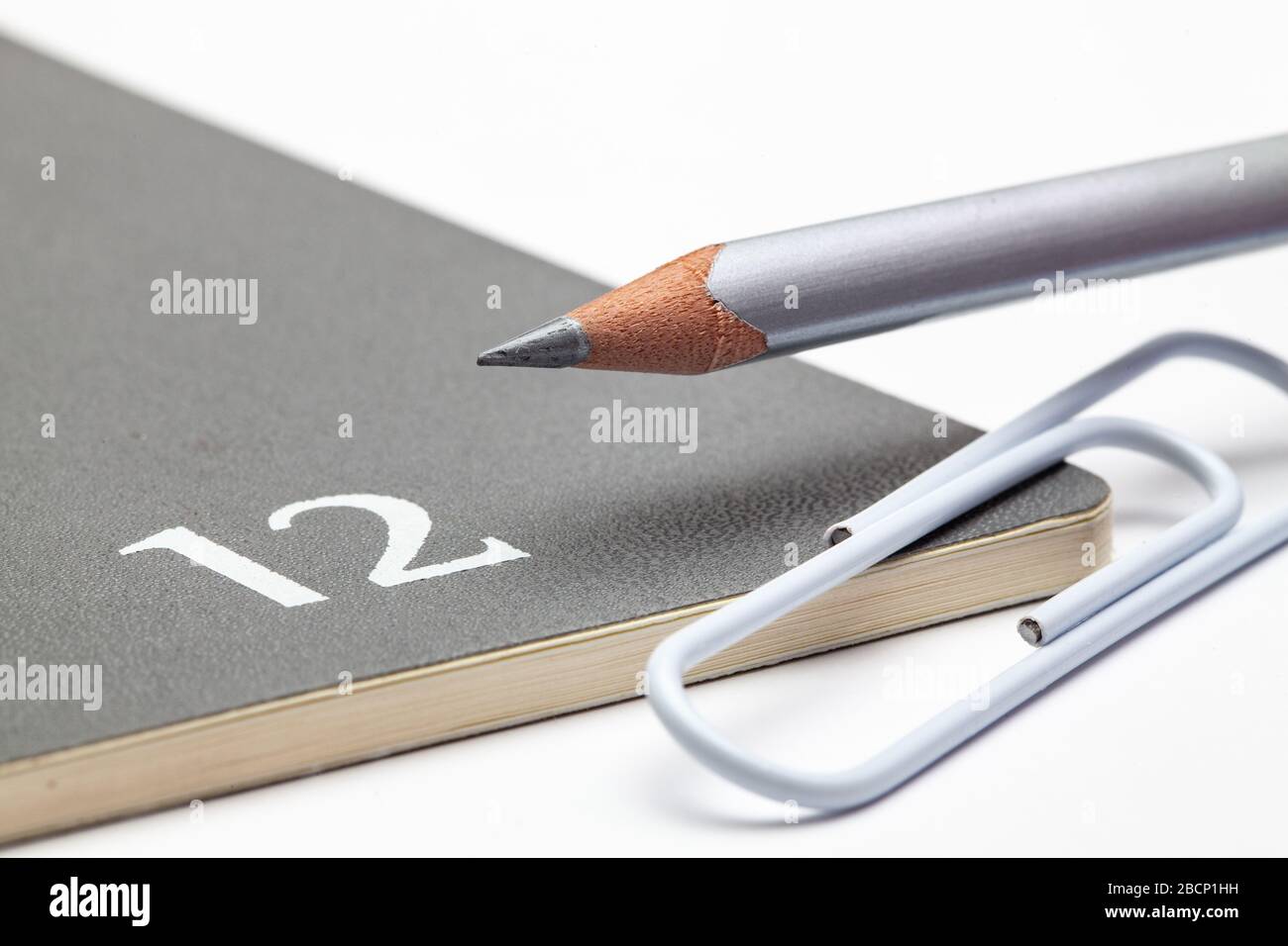 Veranstalter für den Monat Dezember, silberner Bleistift und weiße Büroklammer auf dem weißen Tisch. Stockfoto