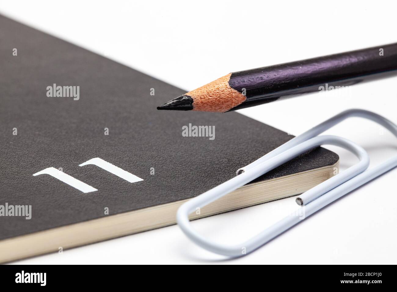 Veranstalter für den Monat November, schwarzer Bleistift und weiße Büroklammer auf dem weißen Tisch. Stockfoto
