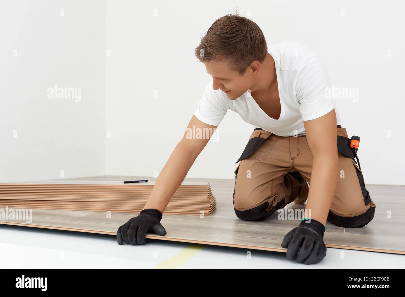 Tischlerarbeiter installieren Laminatboden im Raum. Bauen Sie einen schwimmenden Boden - Bodenbelag - Lagenlaminat Stockfoto