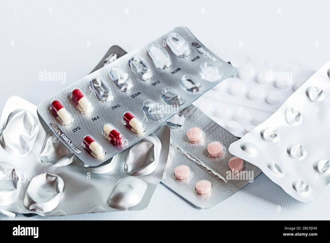 Fünf Packungen verschiedener Medikamente, die nach einem Herzinfarkt (Myokardinfarkt) in silberfarbenen Folienstreifen verschrieben wurden, zufällig ausgelegter, weißer Hintergrund. Stockfoto