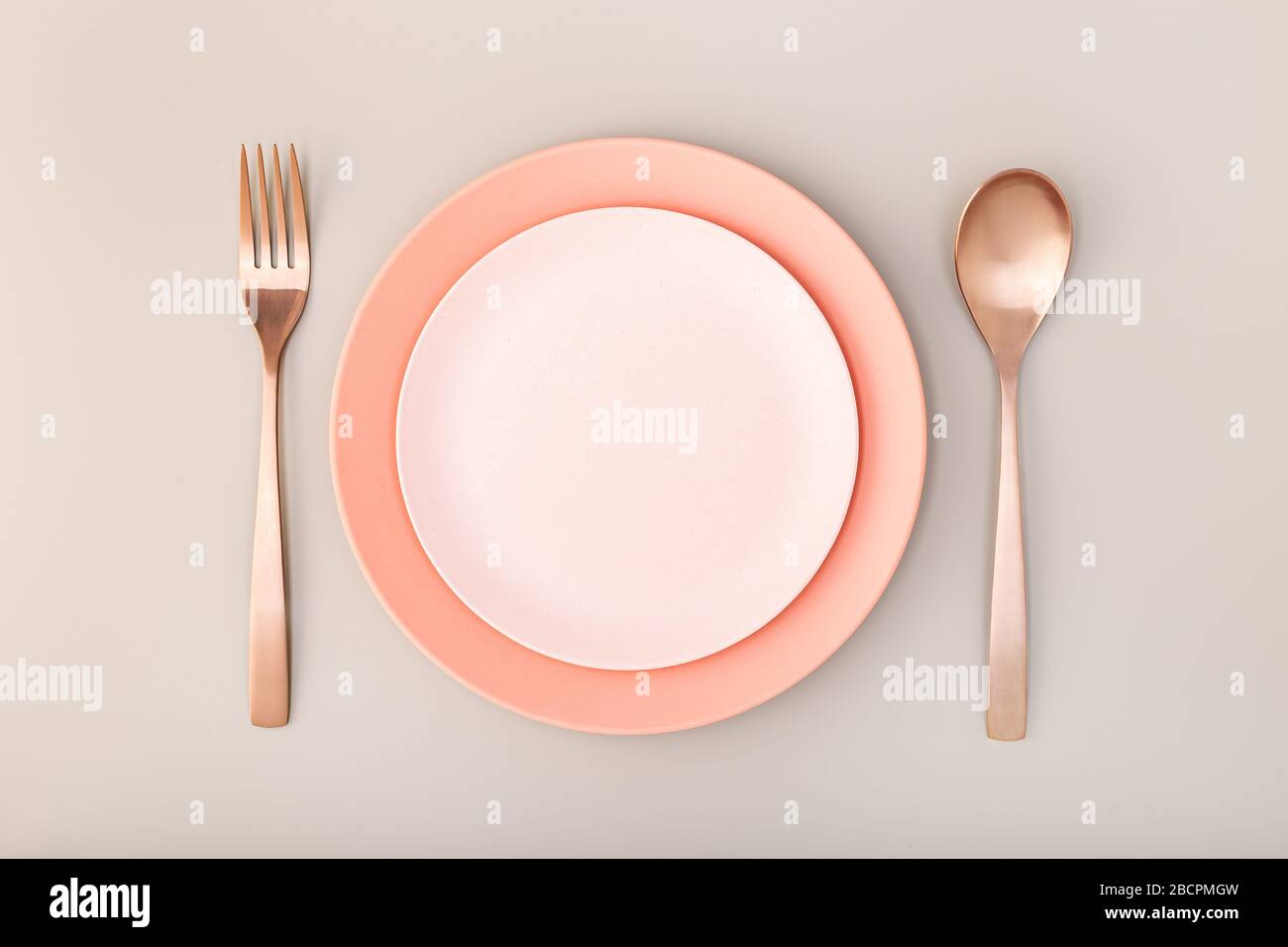 Leere Platte, Gabel und Messer auf dem Tisch. Rosa Pastelltöne. Verspotten Sie sich Stockfoto