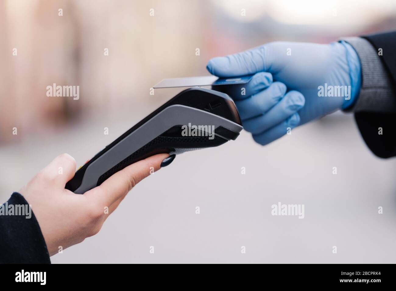 Bargeldlose Zahlung während der Quarantäne. Hand in Gummihandschuhe, Kreditkarte und Zahlungsterminal. Verhinderung der Ausbreitung des Coronavirus. Guter Service während der Pfanne Stockfoto