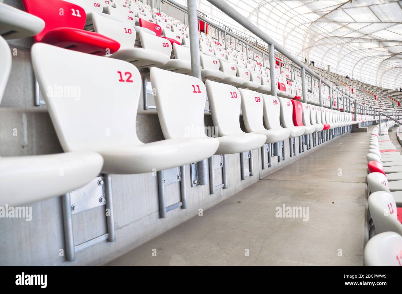 Reihen von Kunststoffsitzen in einem Sportstadion. Die Sitze sind rot-weiß. Stockfoto