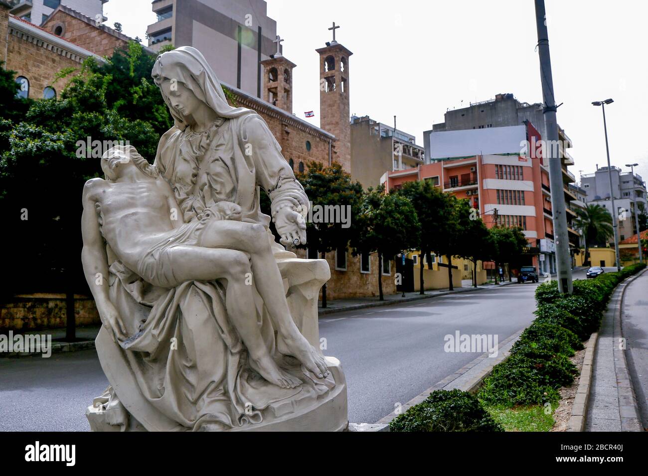 Beirut, Libanon. April 2020. Eine Statue der Jungfrau Maria und des Jesuskindes ist zu sehen, wie sie während des katholischen Palmsonntags einen Kircheneingang in einer menschenleeren Straße schmücken. Die Kirchen des Libanon·haben den bunten Festzug des Palmsonntags abgesagt und die Gottesdienste wurden hinter verschlossenen Türen abgehalten, da Coronavirus (COVID-19) ausbrach. Credit: Marwan Naamani / dpa / Alamy Live News Stockfoto