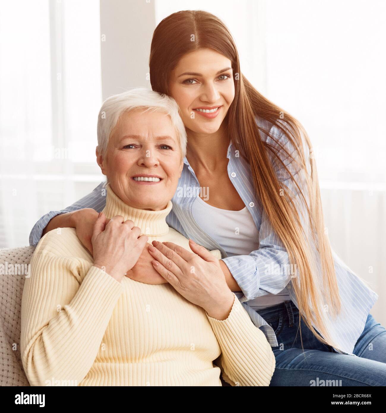 Zwei Generationen. Tochter, die ihre ältere Mutter umarmt Stockfoto