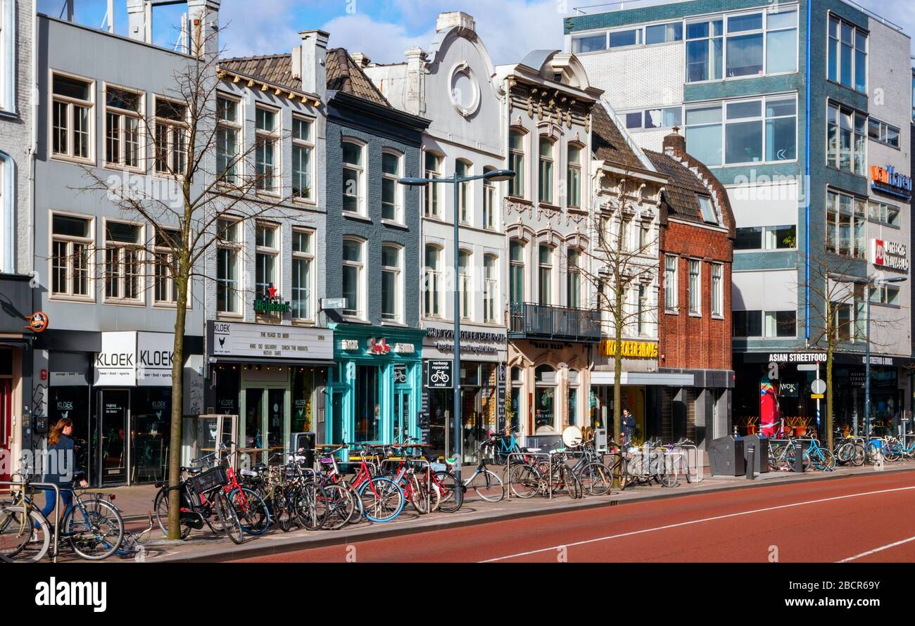 Blick auf die Vredenburg mit Geschäften und geparkten Fahrrädern an einem sonnigen Nachmittag. Die Vredenburg ist Teil des Stadtzentrums von Utrecht. Stockfoto