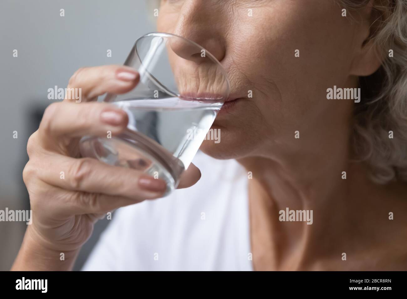 Alte alte Frau, die reines Wasser trinkt. Stockfoto